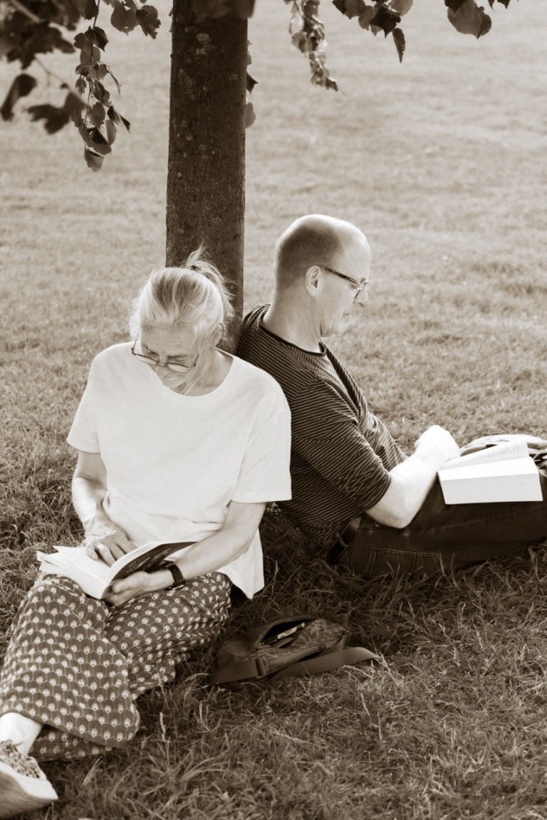 Two people relaxing in a park reading together